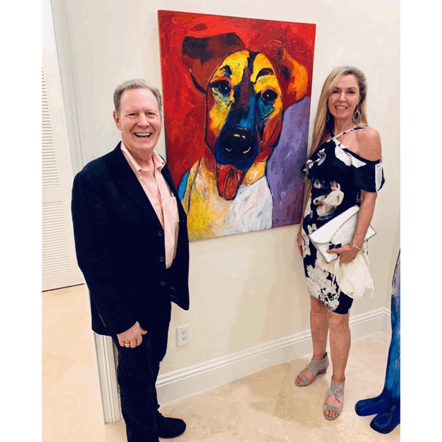 Marcie and Jay Ziv standing beside one of Marcie’s commissioned paintings in a collector’s home